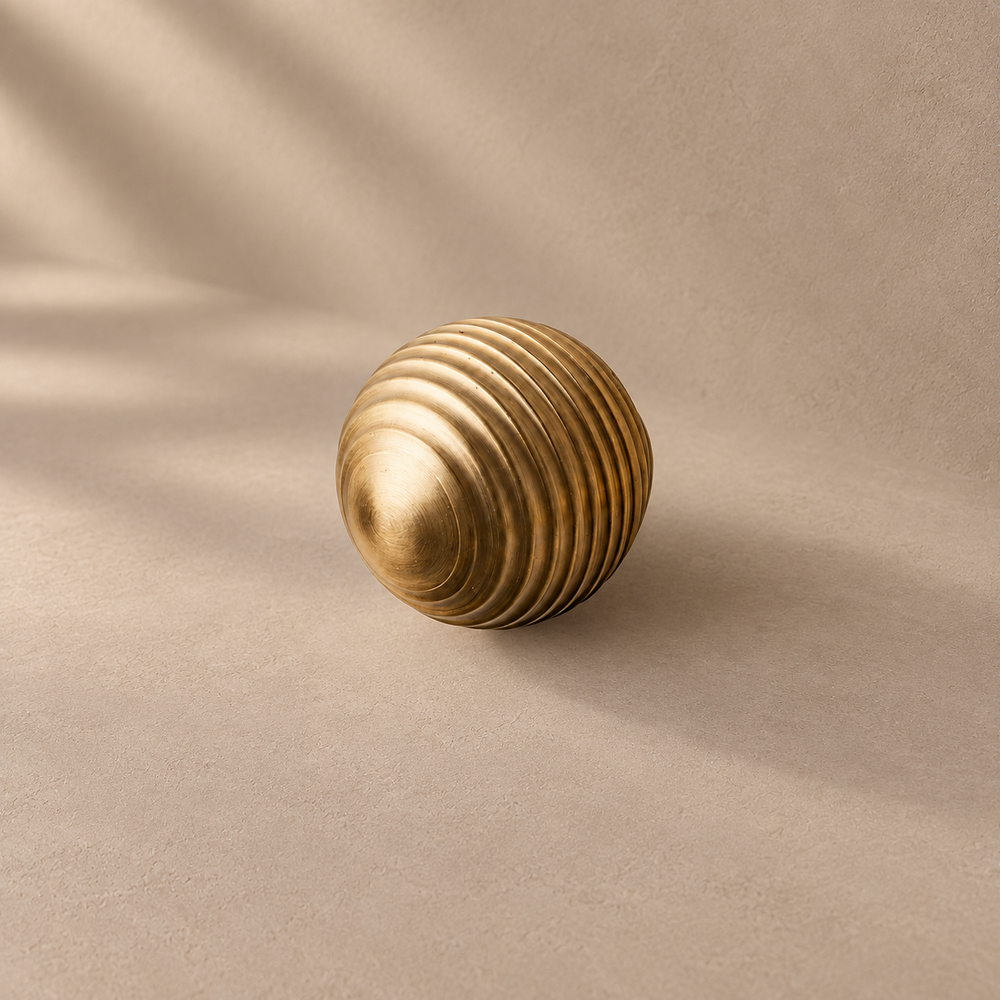 Gold brass thread-ball cabinet knob — ribbed spherical knob on taupe plaster
