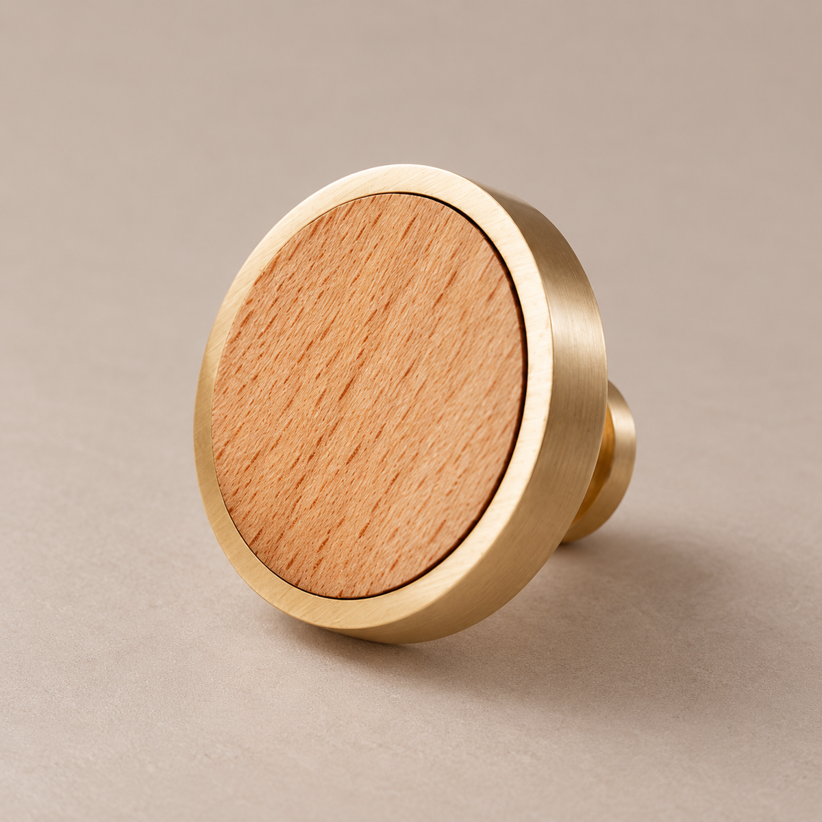 Brushed brass cabinet knob with beech wood inlay on taupe studio background