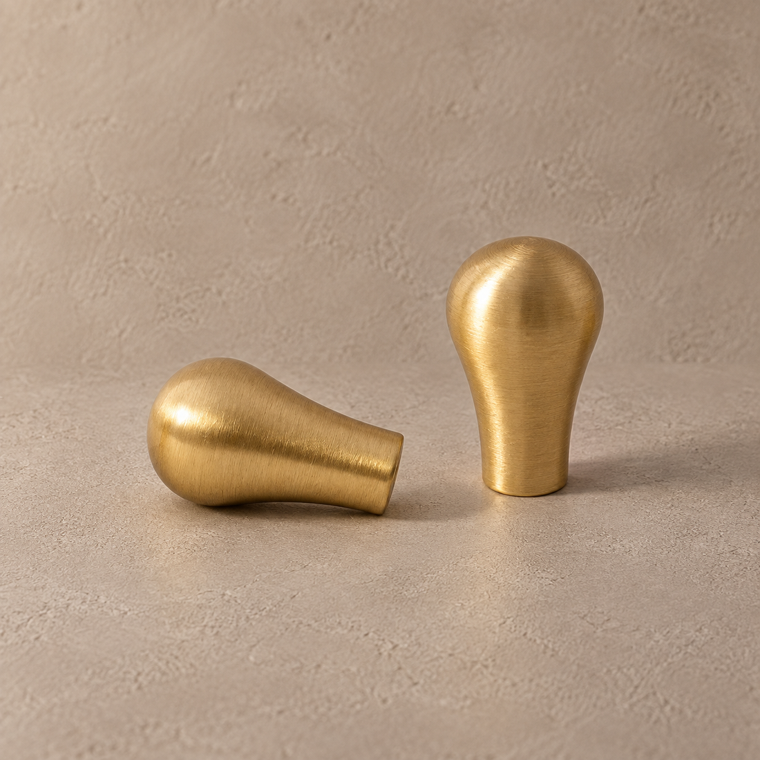 Brushed Brass Teardrop Solid Brass Cabinet Pulls & Knobs on a neutral stone studio background