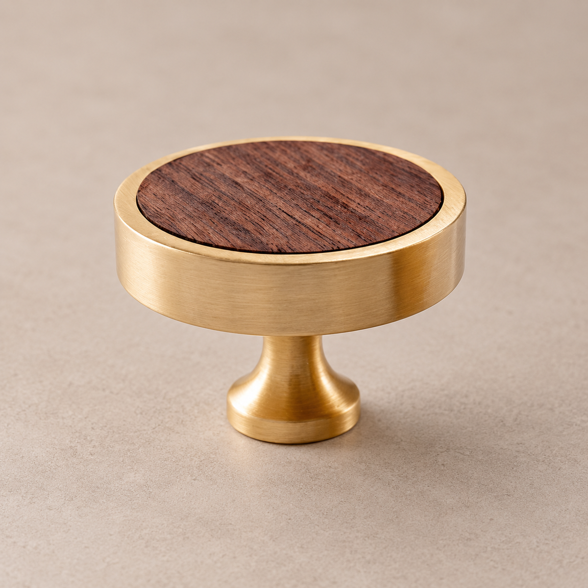 Brushed brass cabinet knob with walnut wood inlay on taupe studio background
