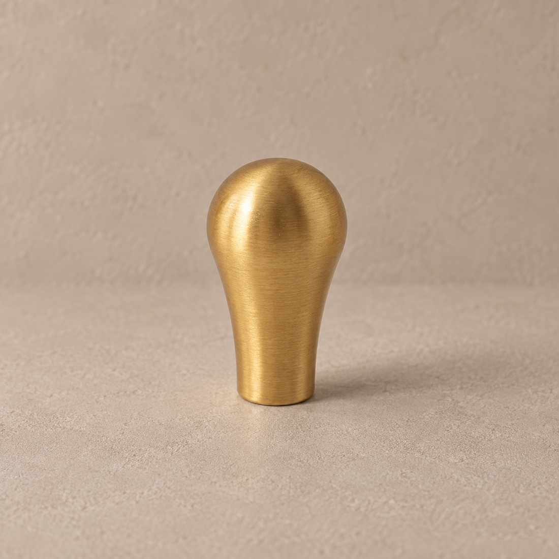 Solid Brushed Brass Cabinet Pull & Knob — Teardrop Design on a neutral stone studio background