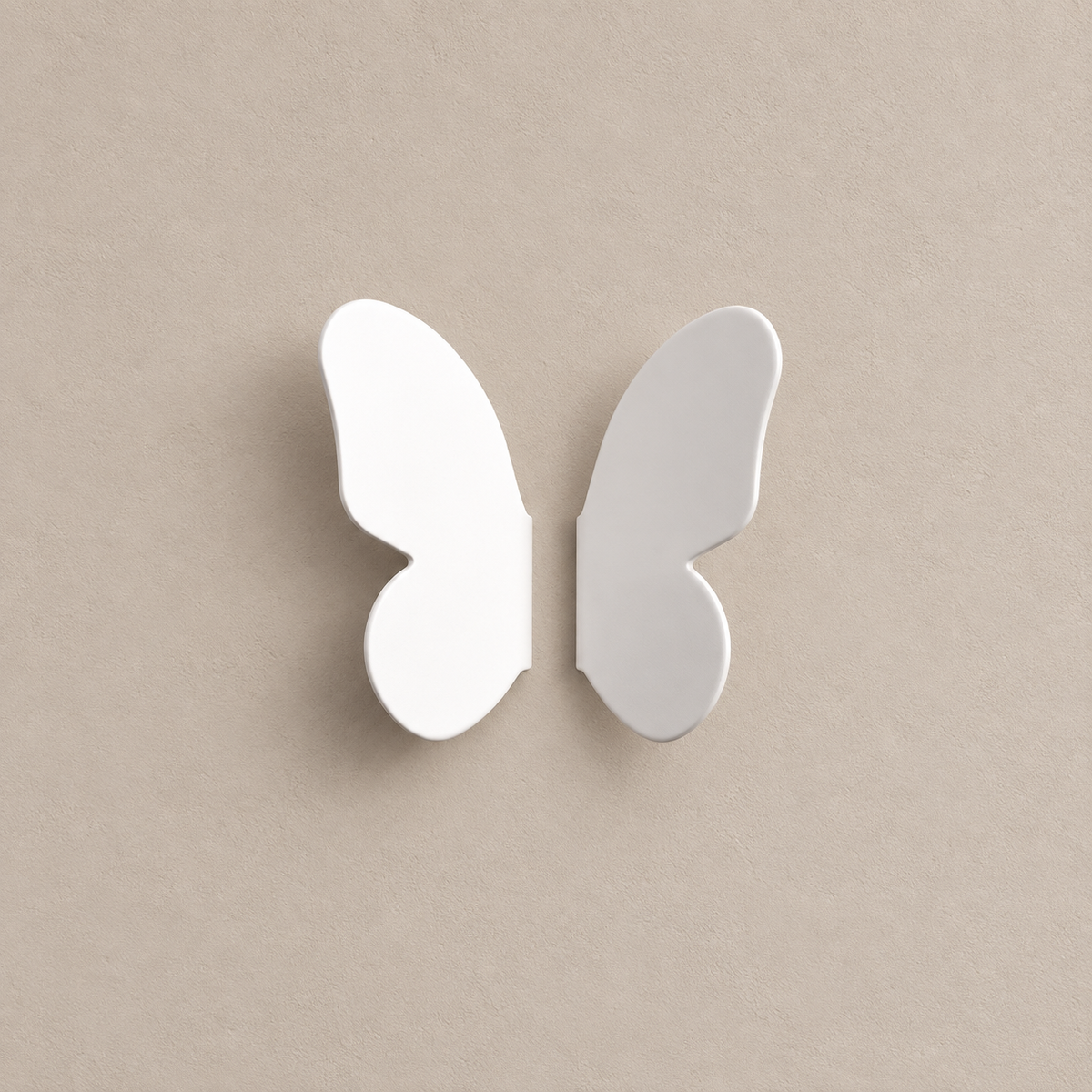 pair of white butterfly-wing cabinet knobs, two separate mirrored wings, matching source quantity and orientations on a warm taupe background