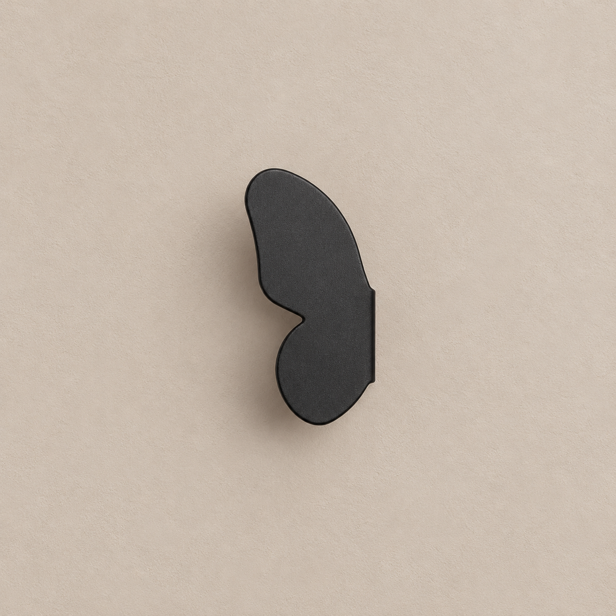 one matte black left butterfly-wing cabinet knob on a warm taupe background