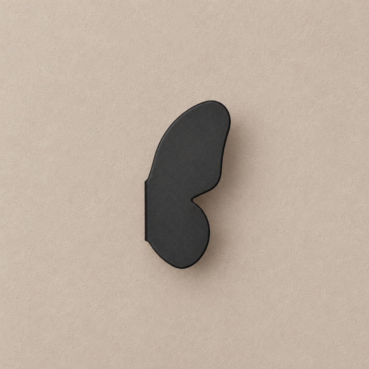 one matte black right butterfly-wing cabinet knob on a warm taupe background
