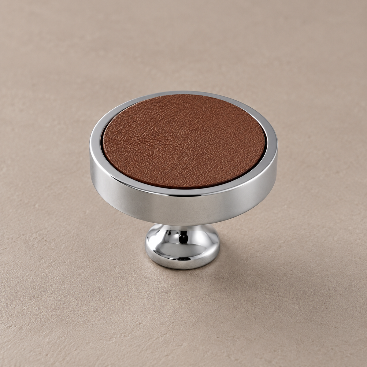 Chrome brass cabinet knob with brown cowhide inlay on taupe studio background