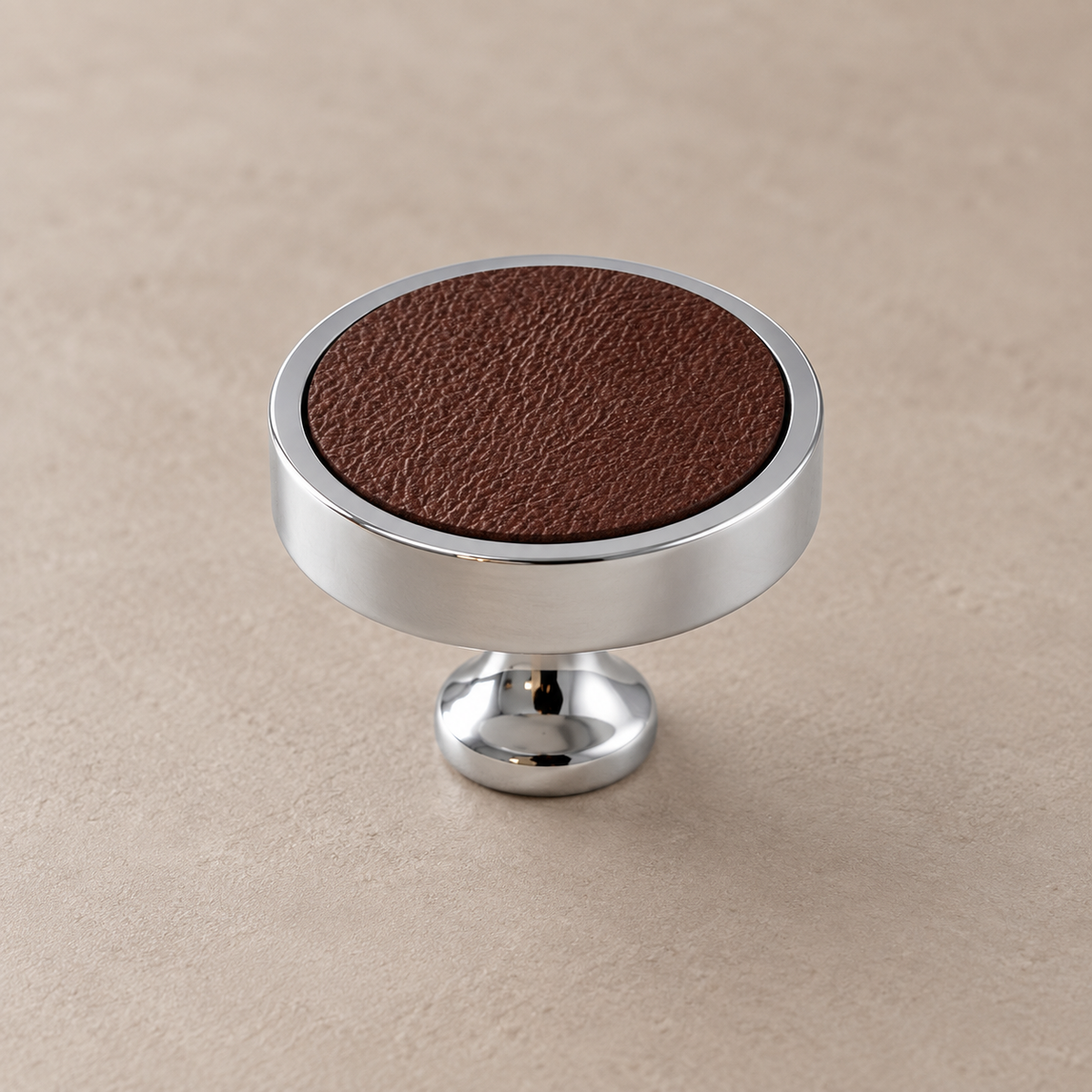 Chrome brass cabinet knob with coffee cowhide inlay on taupe studio background