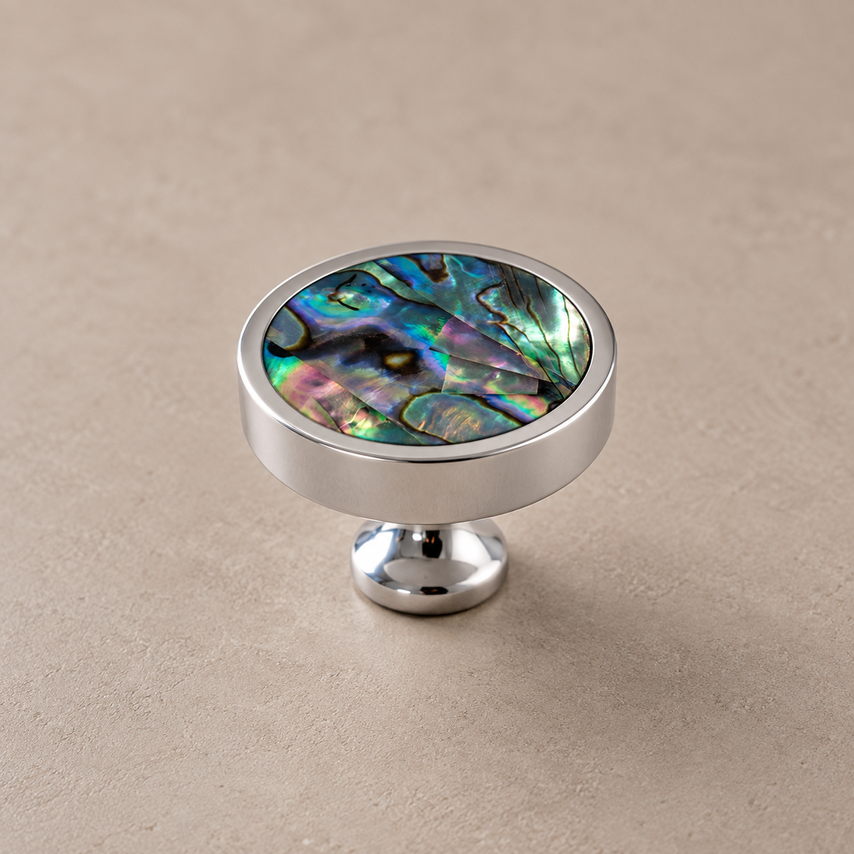 Chrome brass cabinet knob with green shell inlay on taupe studio background