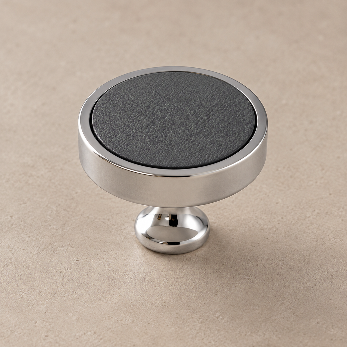 Chrome brass cabinet knob with grey cowhide inlay on taupe studio background
