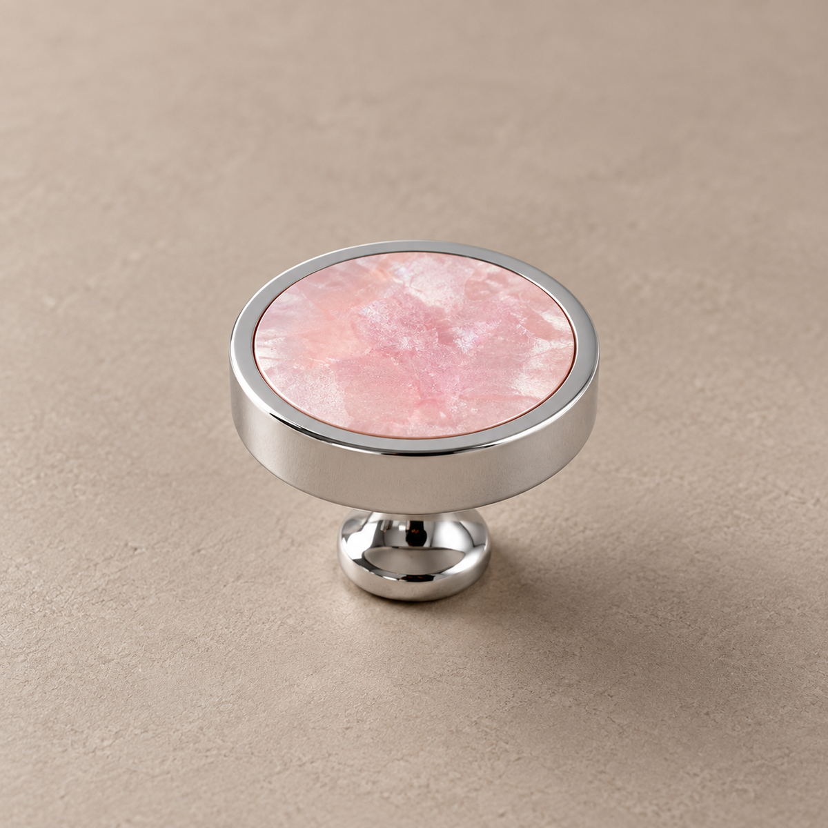 Chrome brass cabinet knob with pink shell inlay on taupe studio background