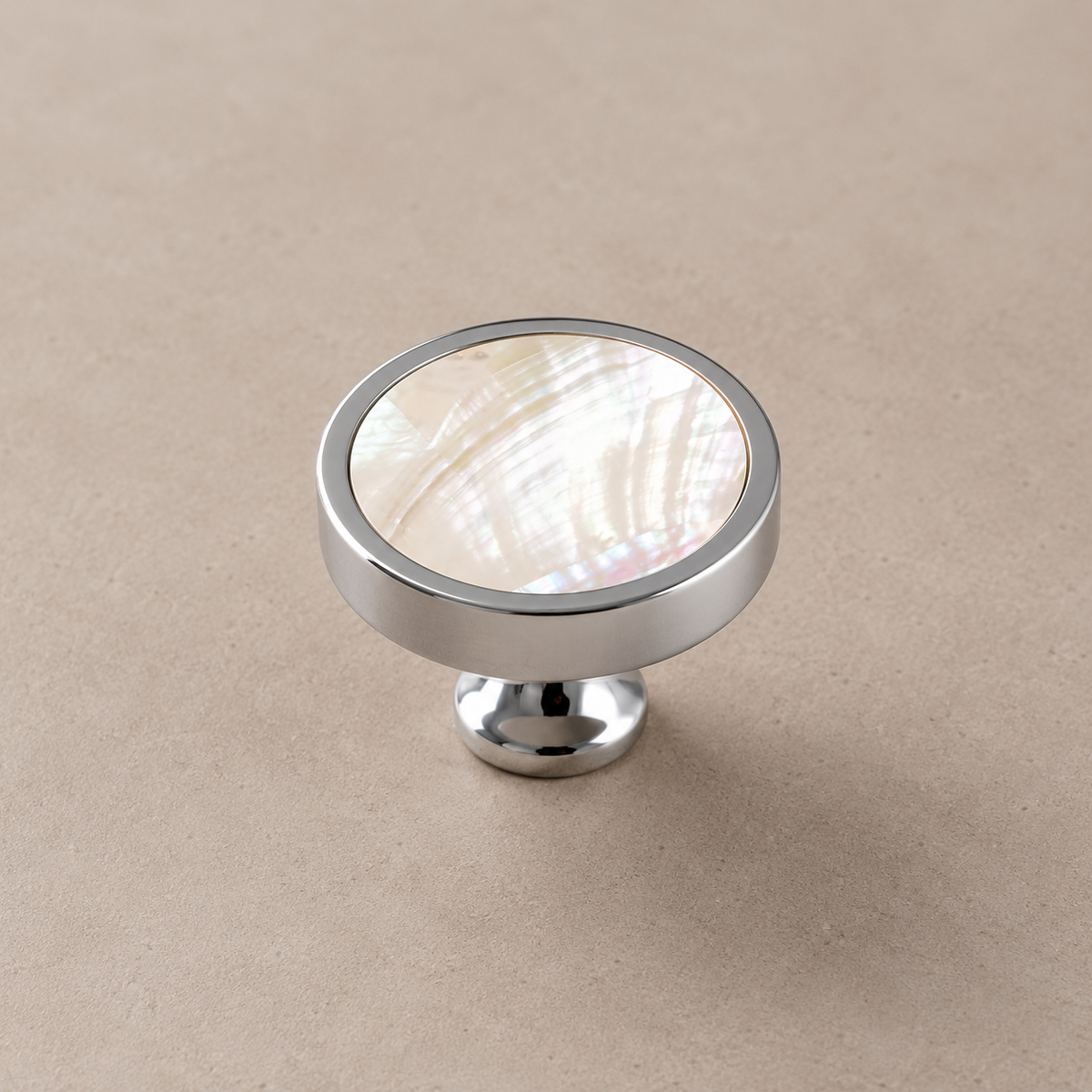 Chrome brass cabinet knob with white shell inlay on taupe studio background