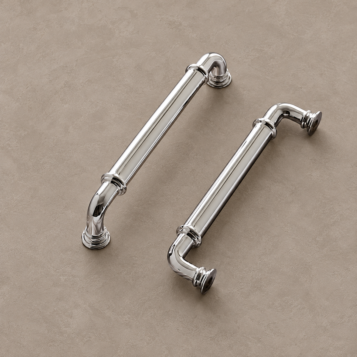 Chrome cabinet pulls with ringed collars and stepped mounting feet on taupe plaster