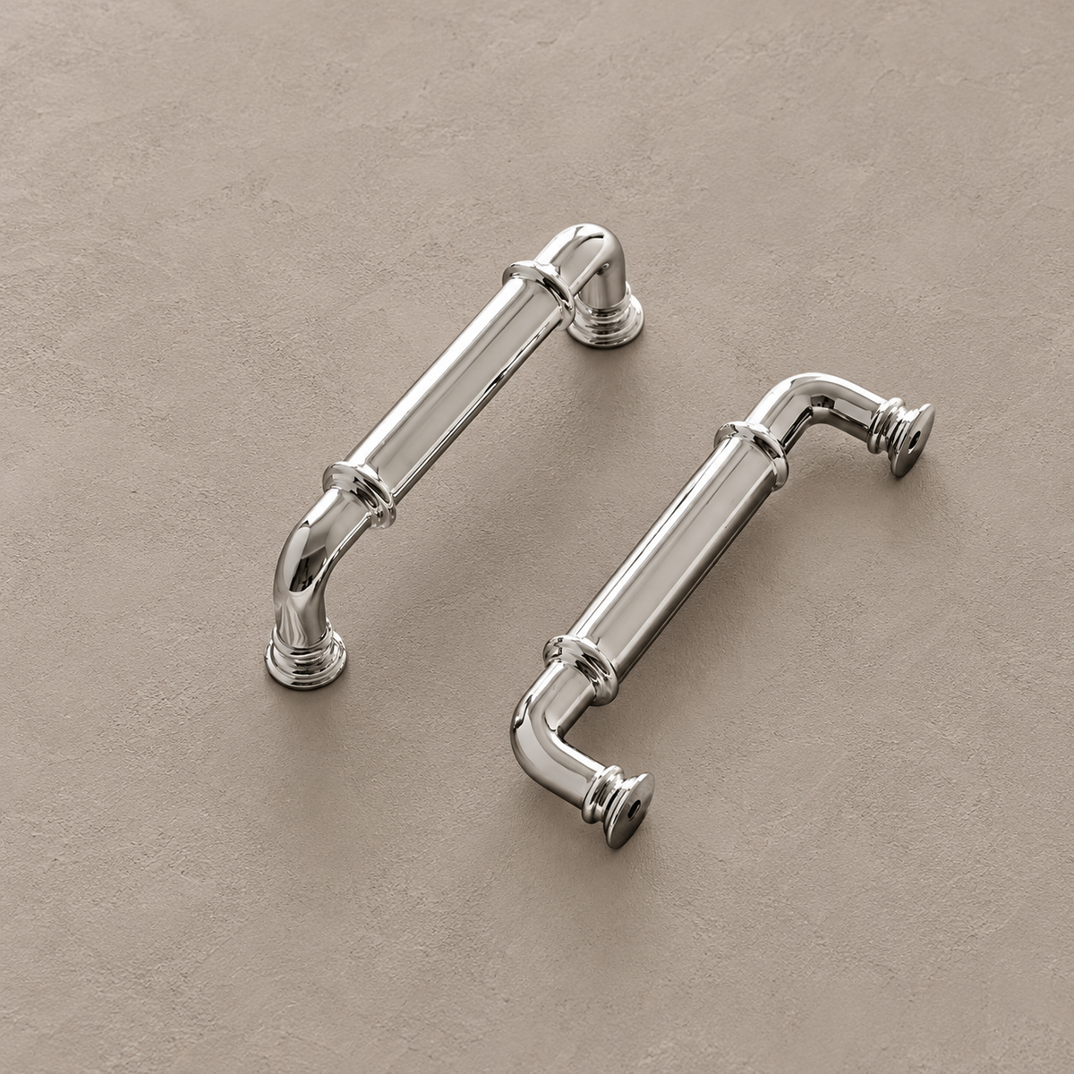 Chrome cabinet pulls with ringed collars and stepped mounting feet on taupe plaster
