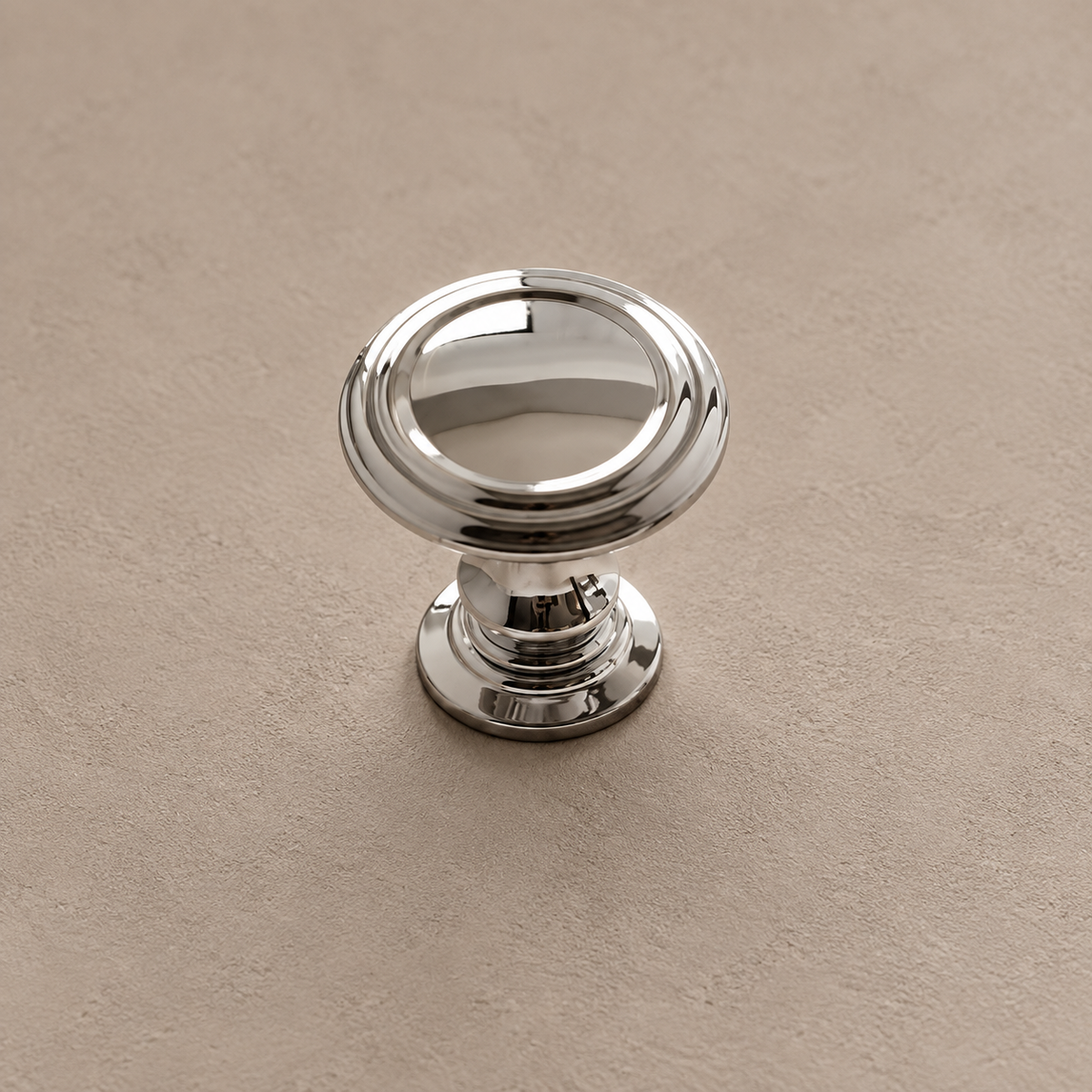Chrome silver round cabinet knob with stepped base on taupe plaster