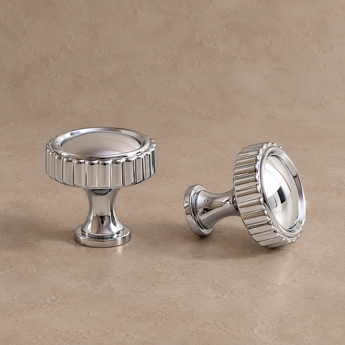 polished chrome knob with vertically fluted rim, inset smooth round face and flared pedestal on a warm taupe studio background