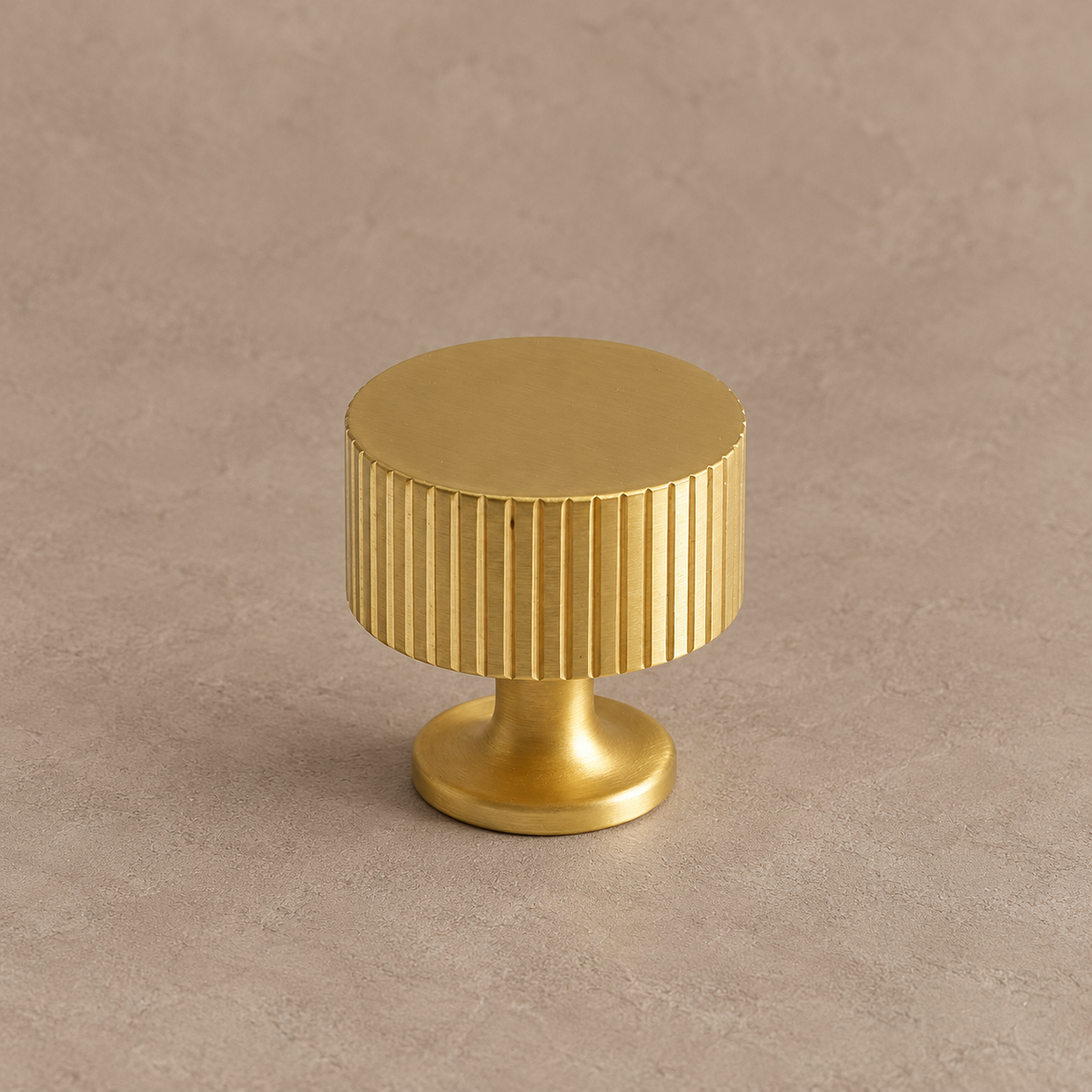 brushed brass fluted cabinet knob on warm taupe studio background