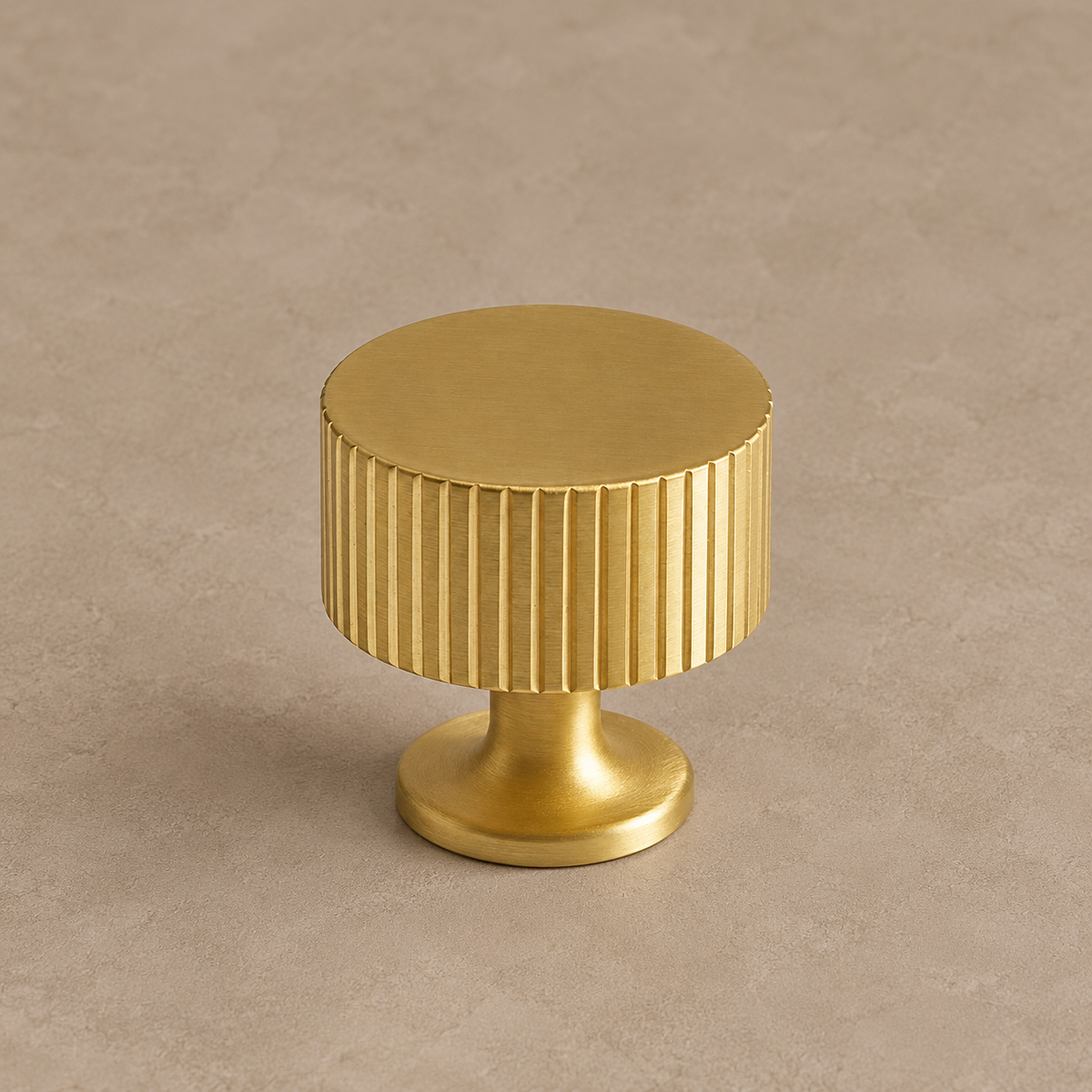 brushed brass fluted cabinet knob on warm taupe studio background