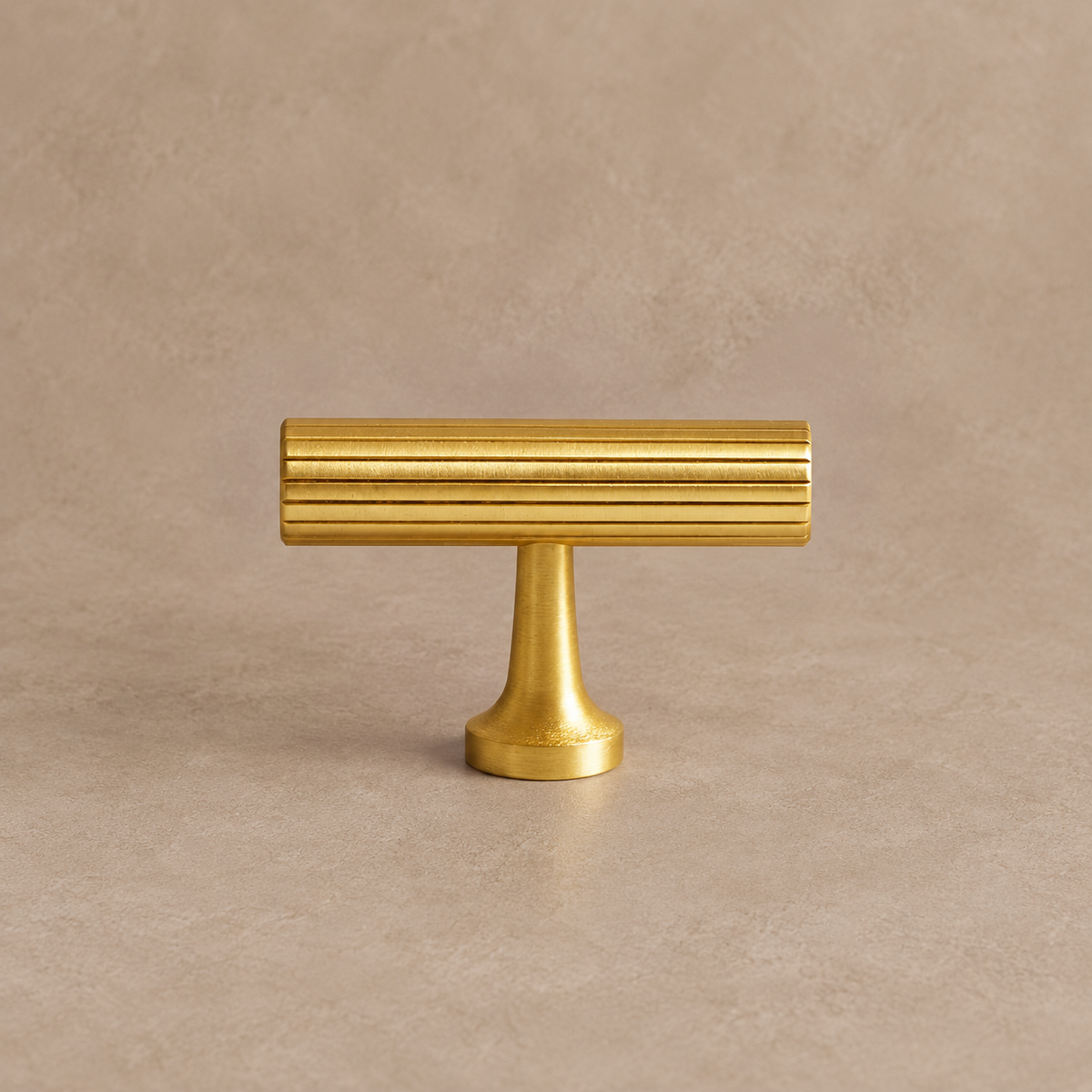 brushed brass fluted cabinet knob on warm taupe studio background