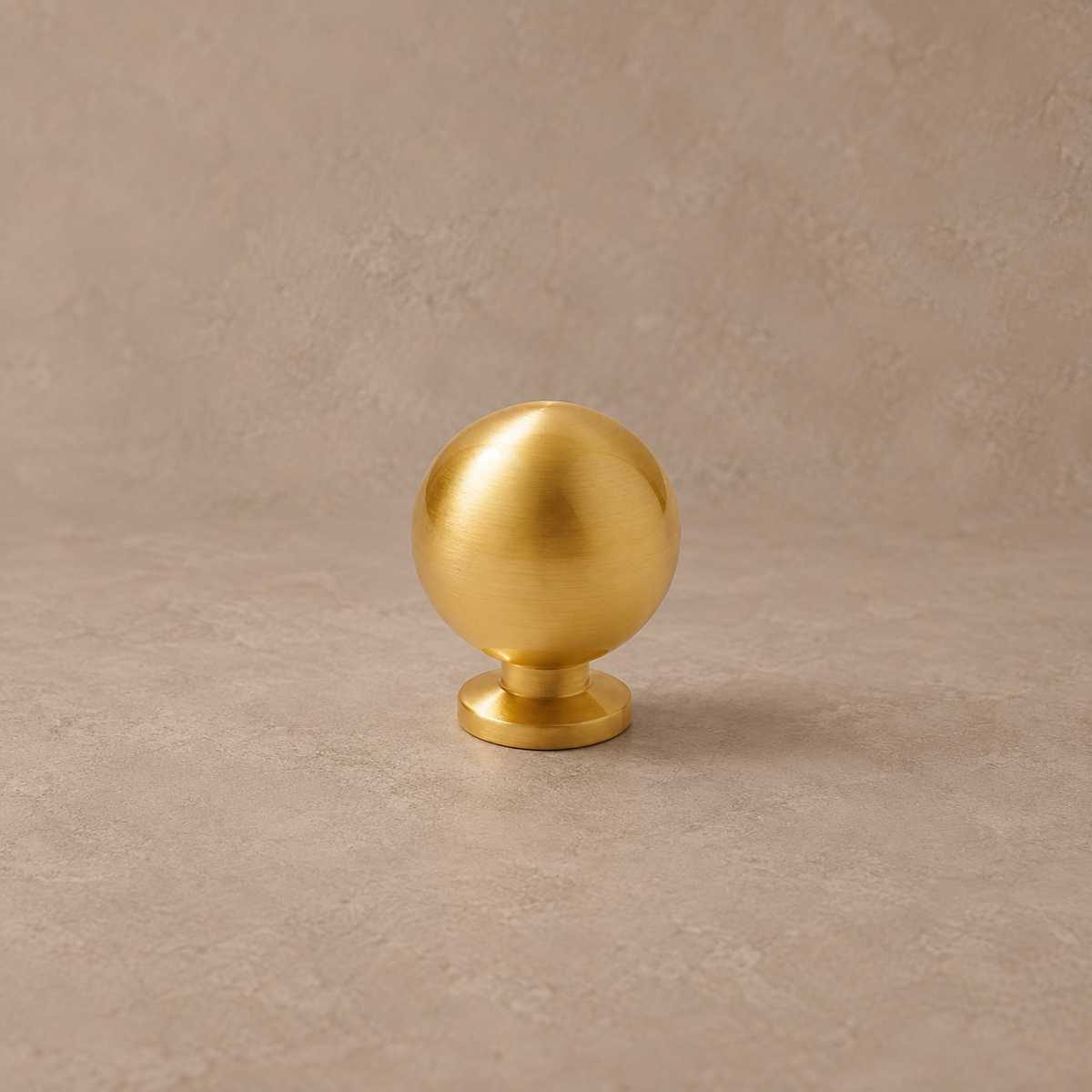 Gold brass ball cabinet knob with round pedestal on taupe studio background
