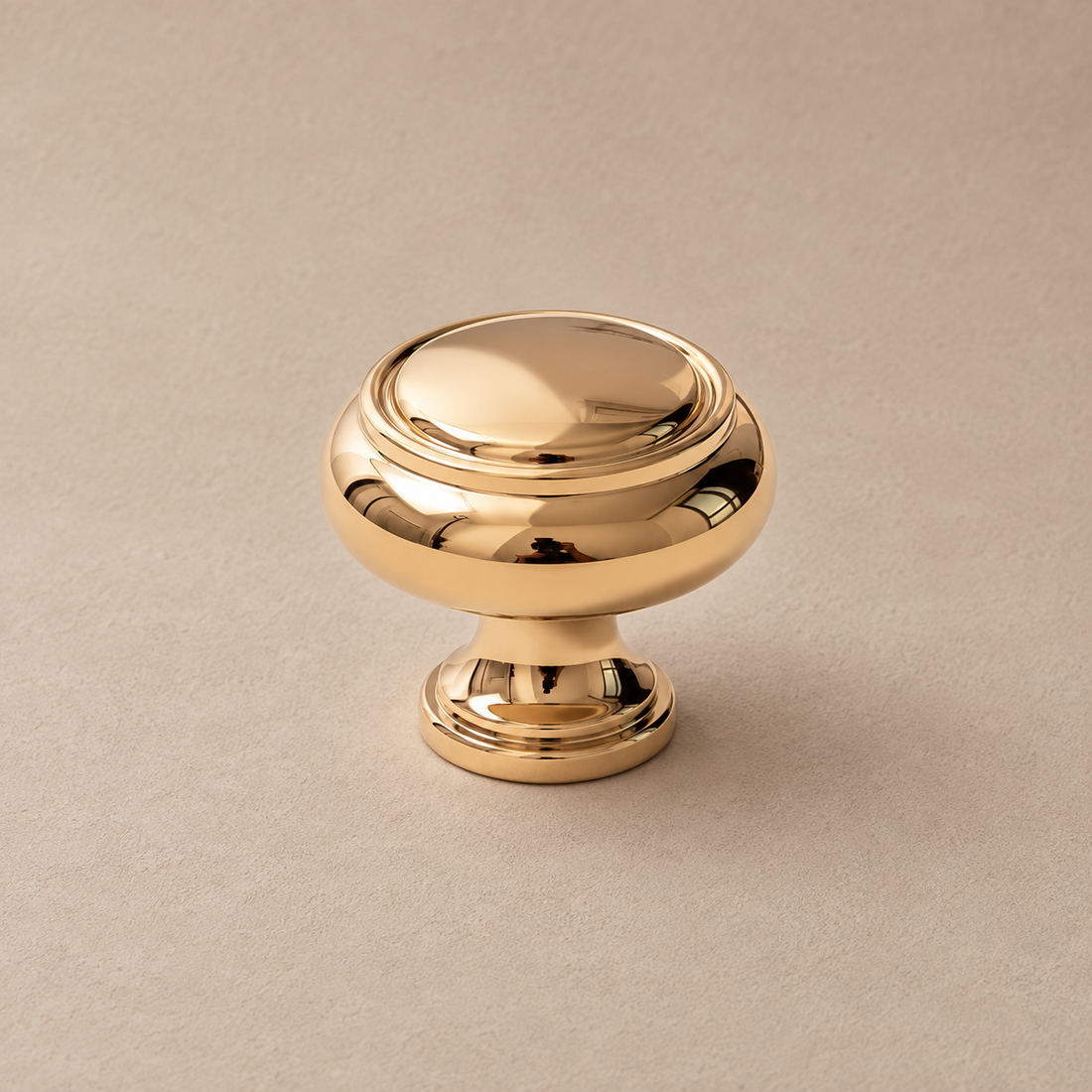 Polished gold spindle cabinet pull with round pedestal feet on a deep olive studio background