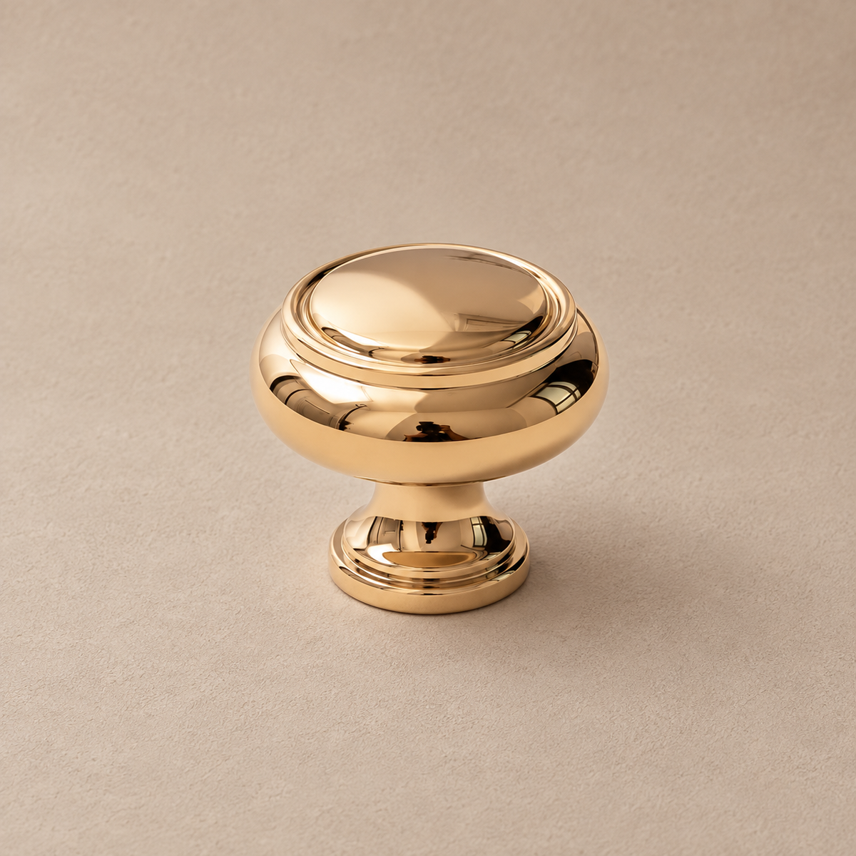 Polished gold round cabinet knob detail on taupe plaster