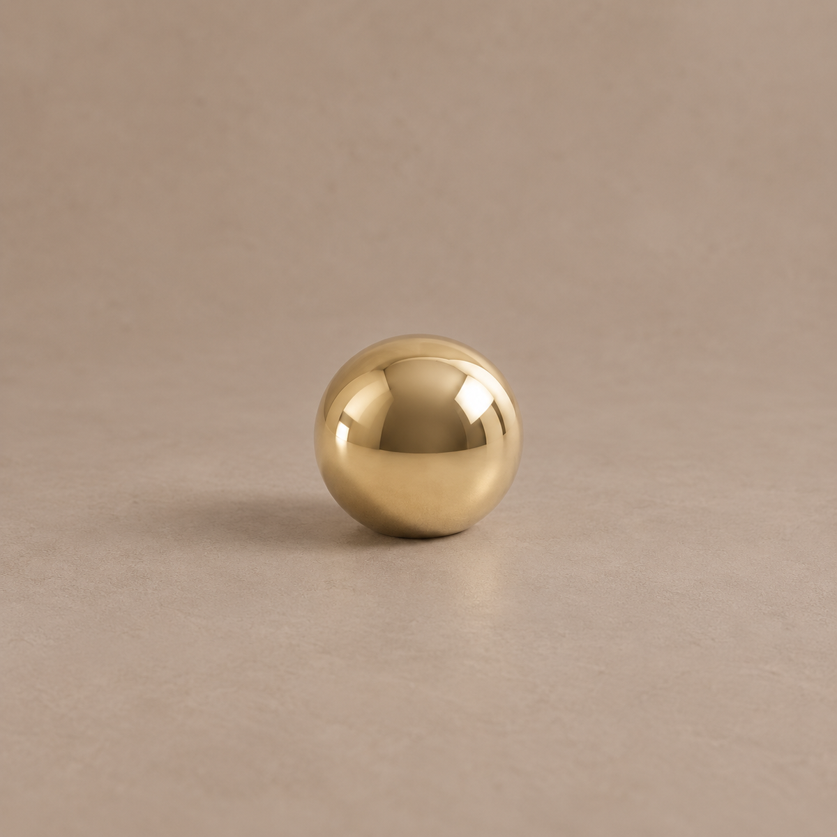 Polished brass ball cabinet knob on a taupe studio background