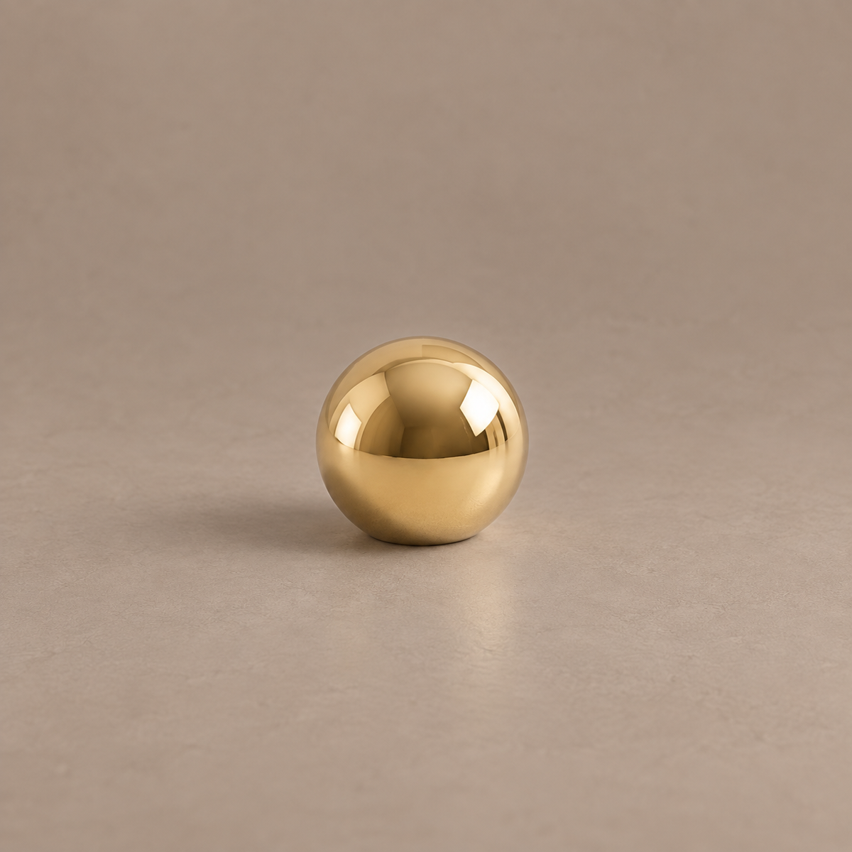 Polished brass ball cabinet knob on a taupe studio background
