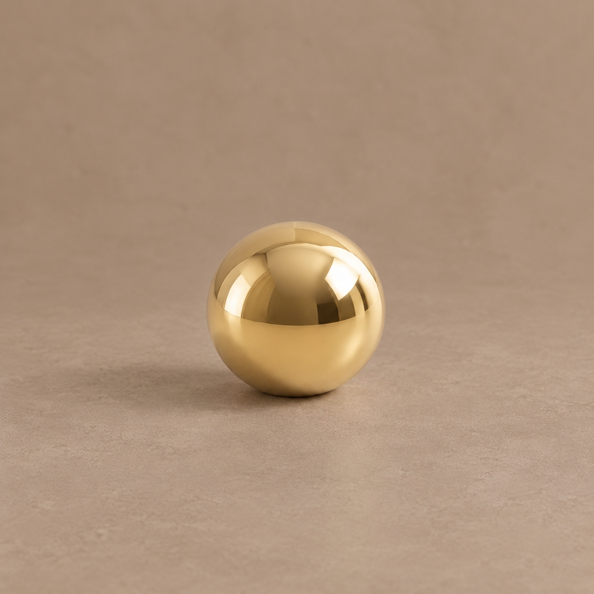 Polished brass ball cabinet knob on a taupe studio background