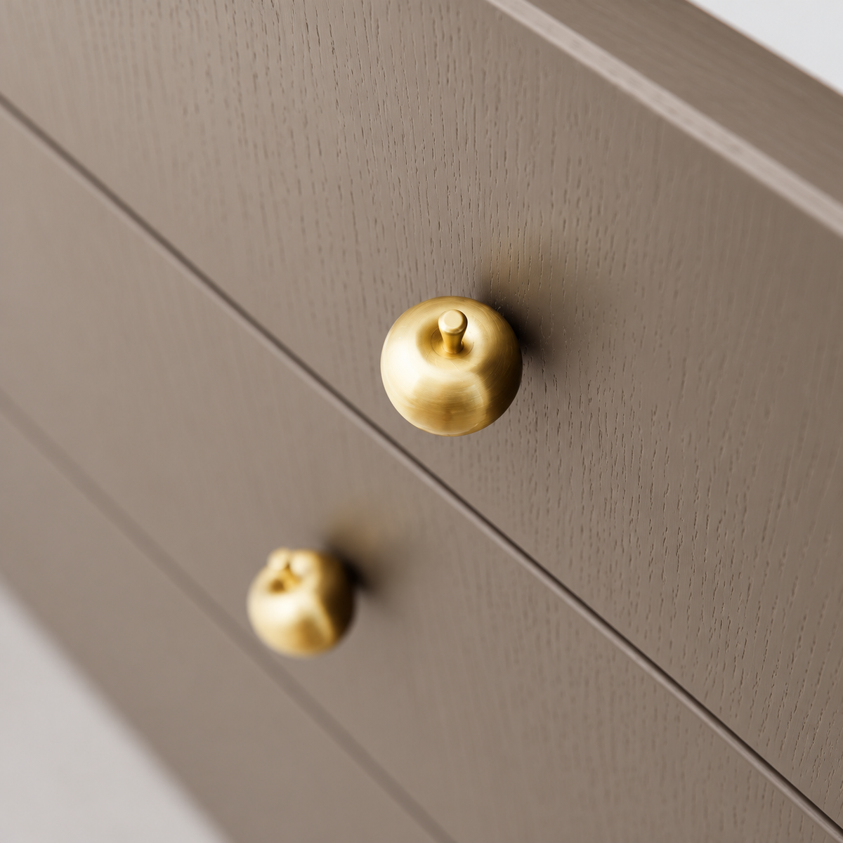 Brass apple knobs mounted on taupe wood drawers