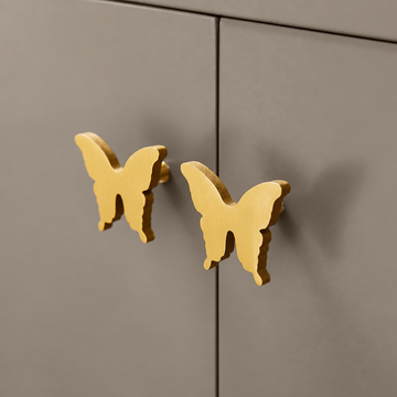 Brass butterfly cabinet knobs mounted on taupe doors