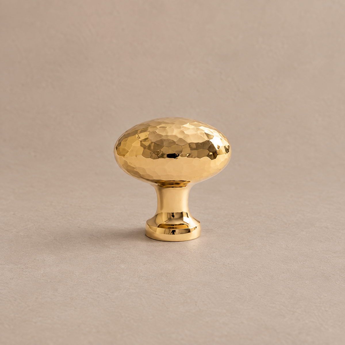 polished brass hammered oval knob on warm taupe studio surface