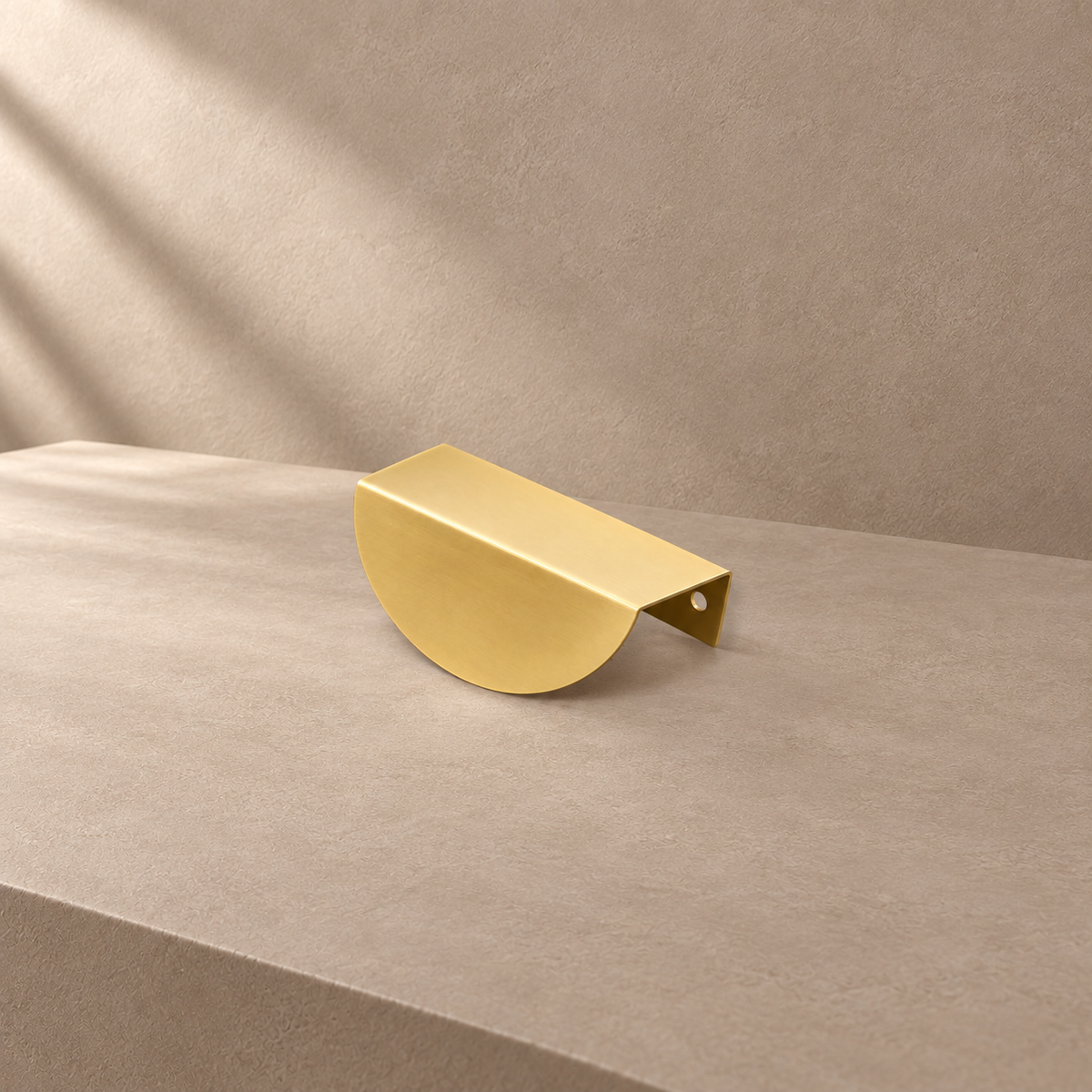 Rounded brass leaf edge pull on a warm taupe studio surface