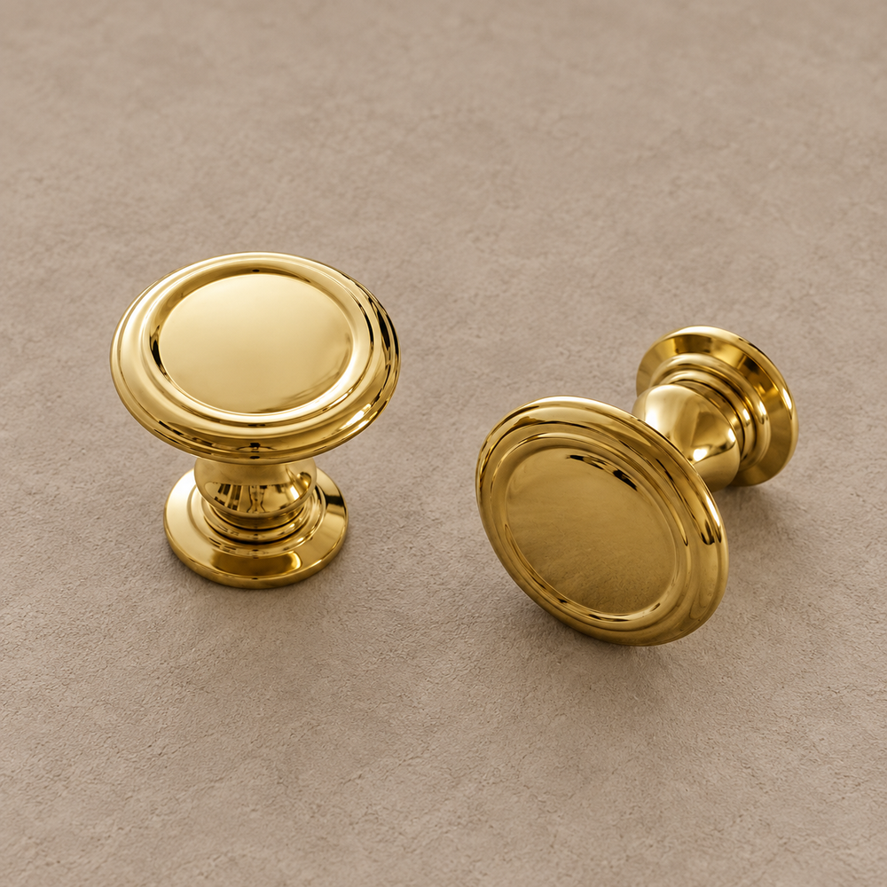 Polished brass round cabinet knobs with raised ring rims, front and side views on taupe