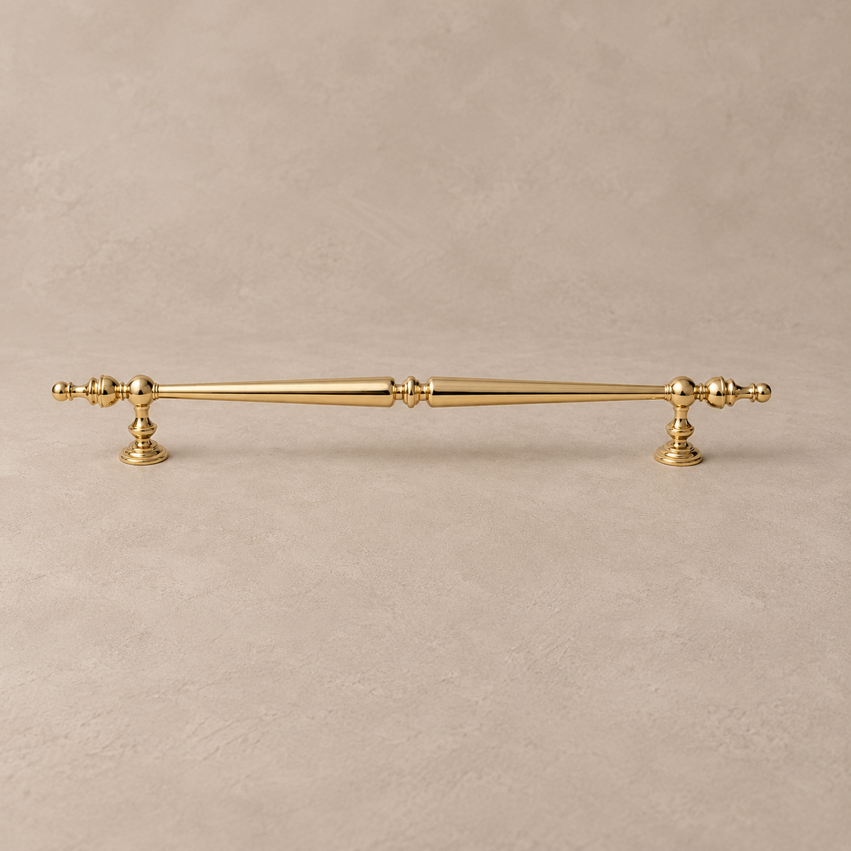 polished brass spindle pull on a warm taupe studio surface