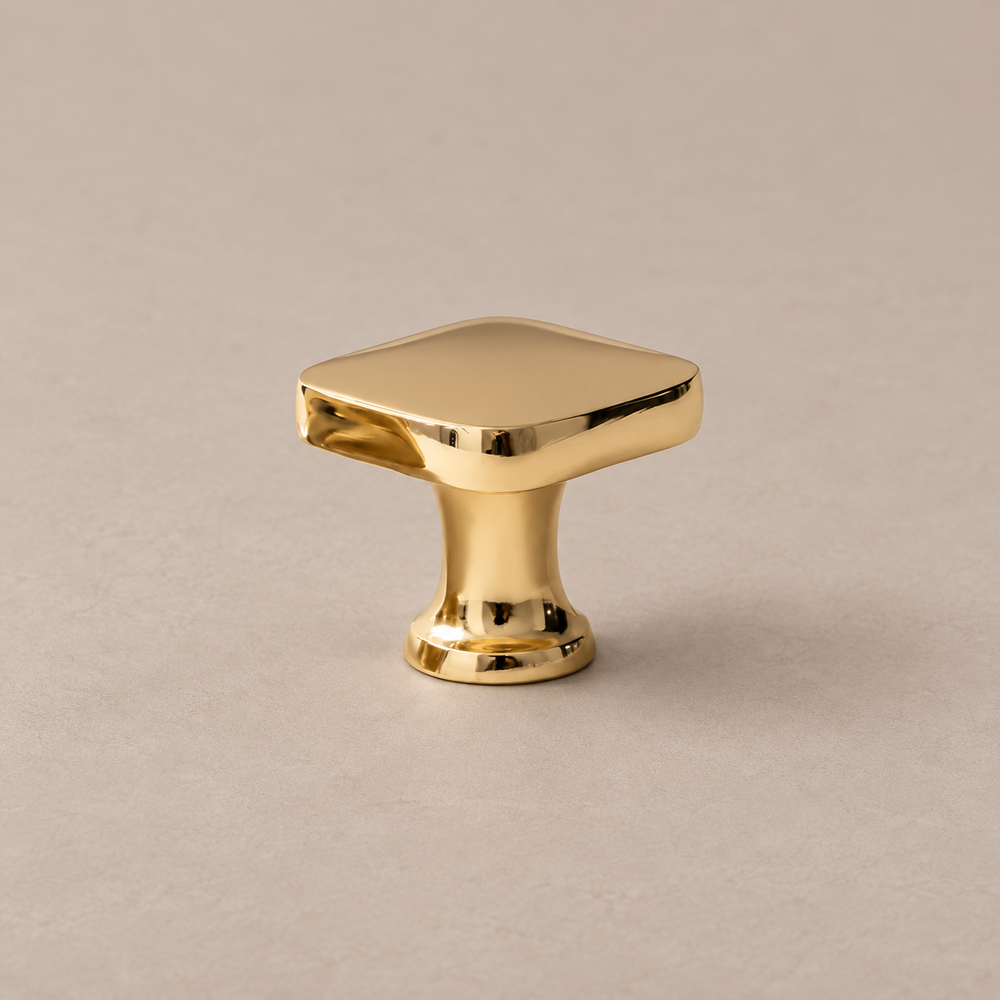 polished brass square knob on warm taupe studio surface