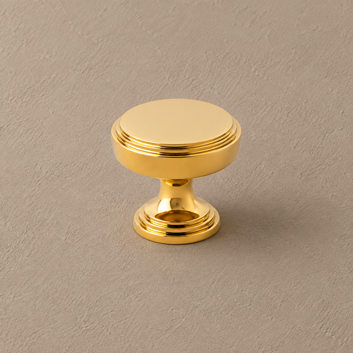 Polished gold cabinet round knob detail on taupe plaster