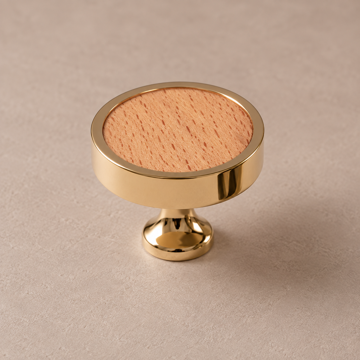 Polished PVD brass cabinet knob with beech inlay on taupe studio background