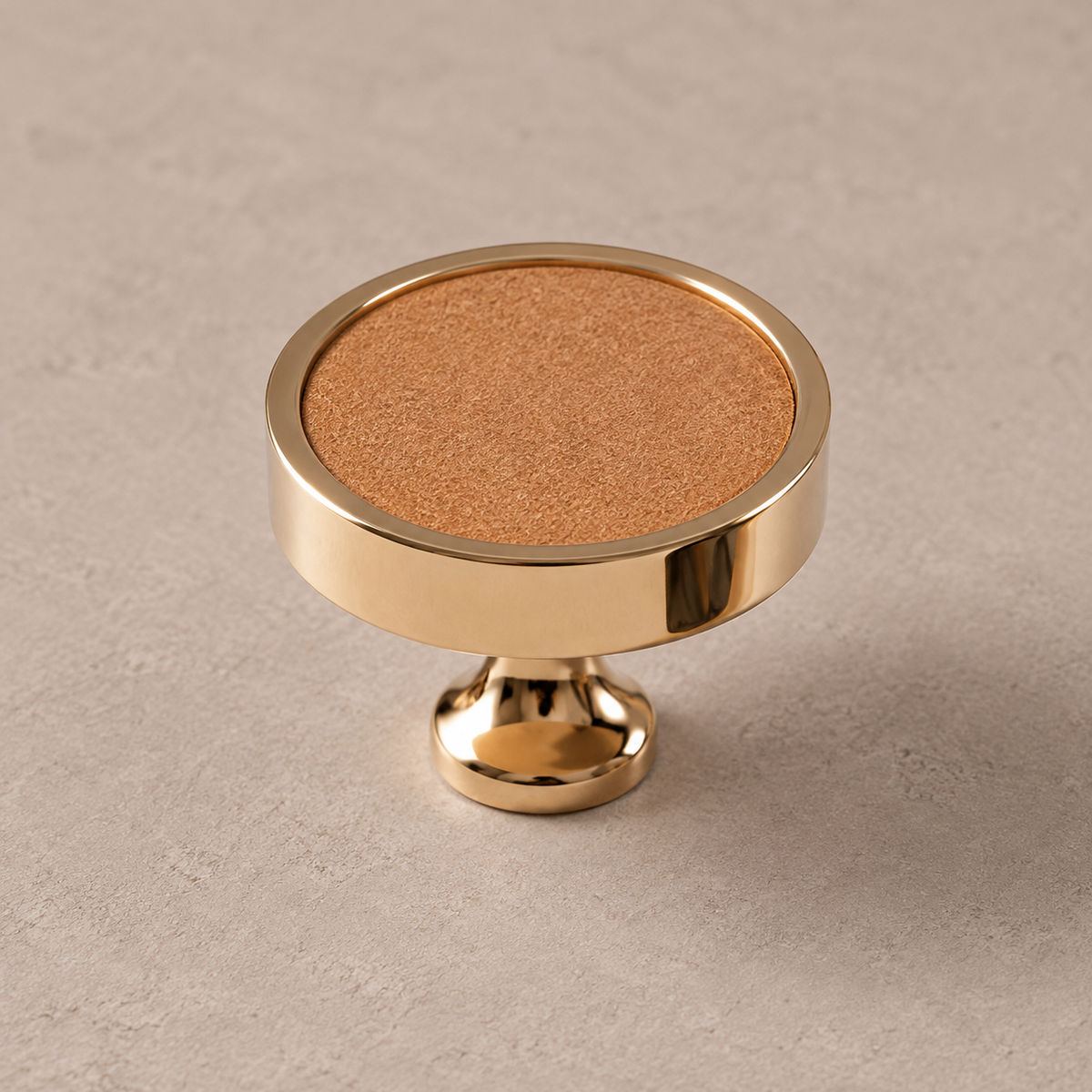 Polished PVD brass cabinet knob with khaki cowhide leather inlay on taupe studio background
