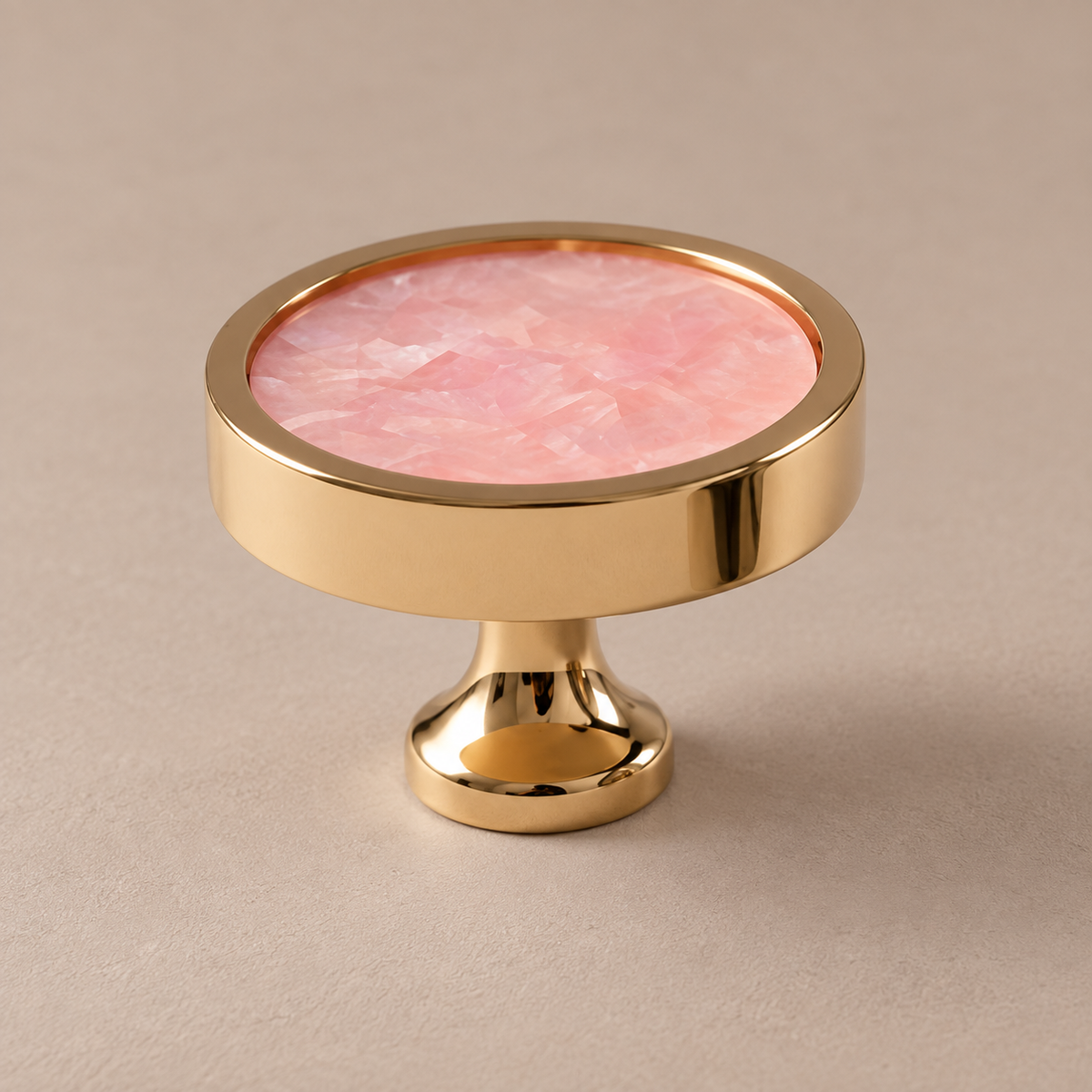 Polished PVD brass cabinet knob with pink shell inlay on taupe studio background