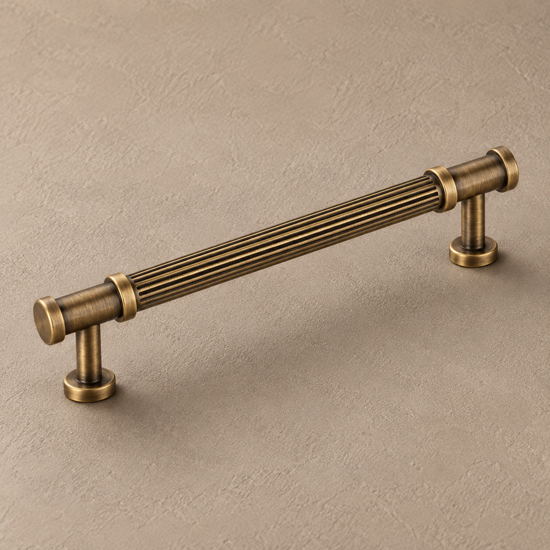 Antique brass ribbed cabinet pull on warm taupe plaster