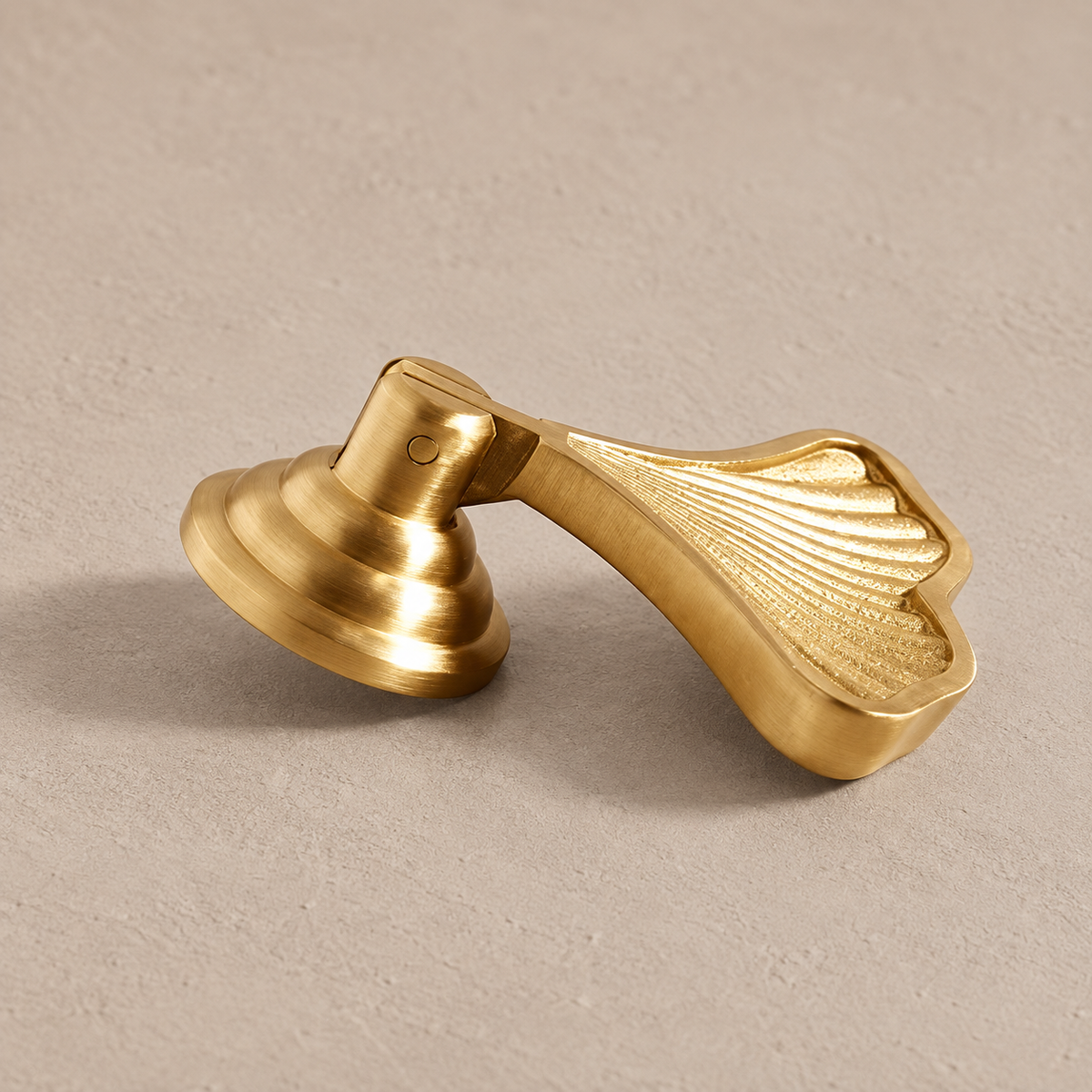 Gold sculpted ginkgo leaf cabinet knob on taupe plaster