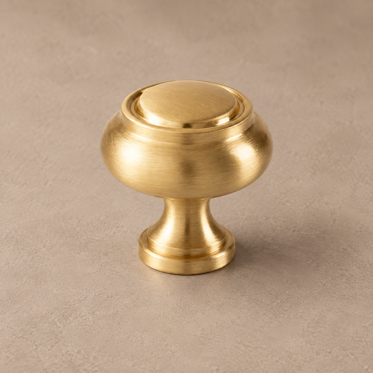 Brushed brass round cabinet knob detail on taupe plaster